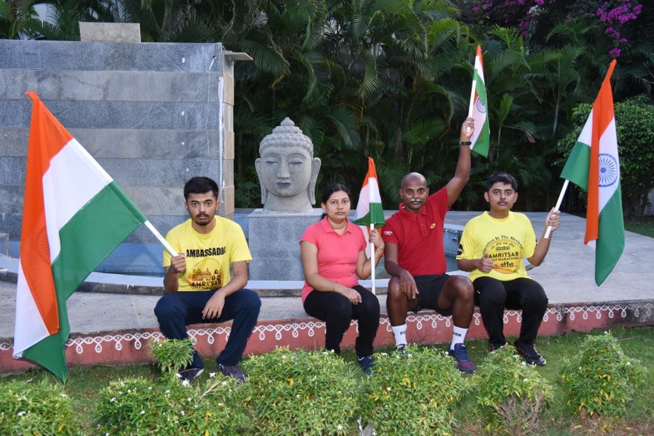 Bobba Ravinder Reddy and family holding Indian flags in front of a Buddha statue