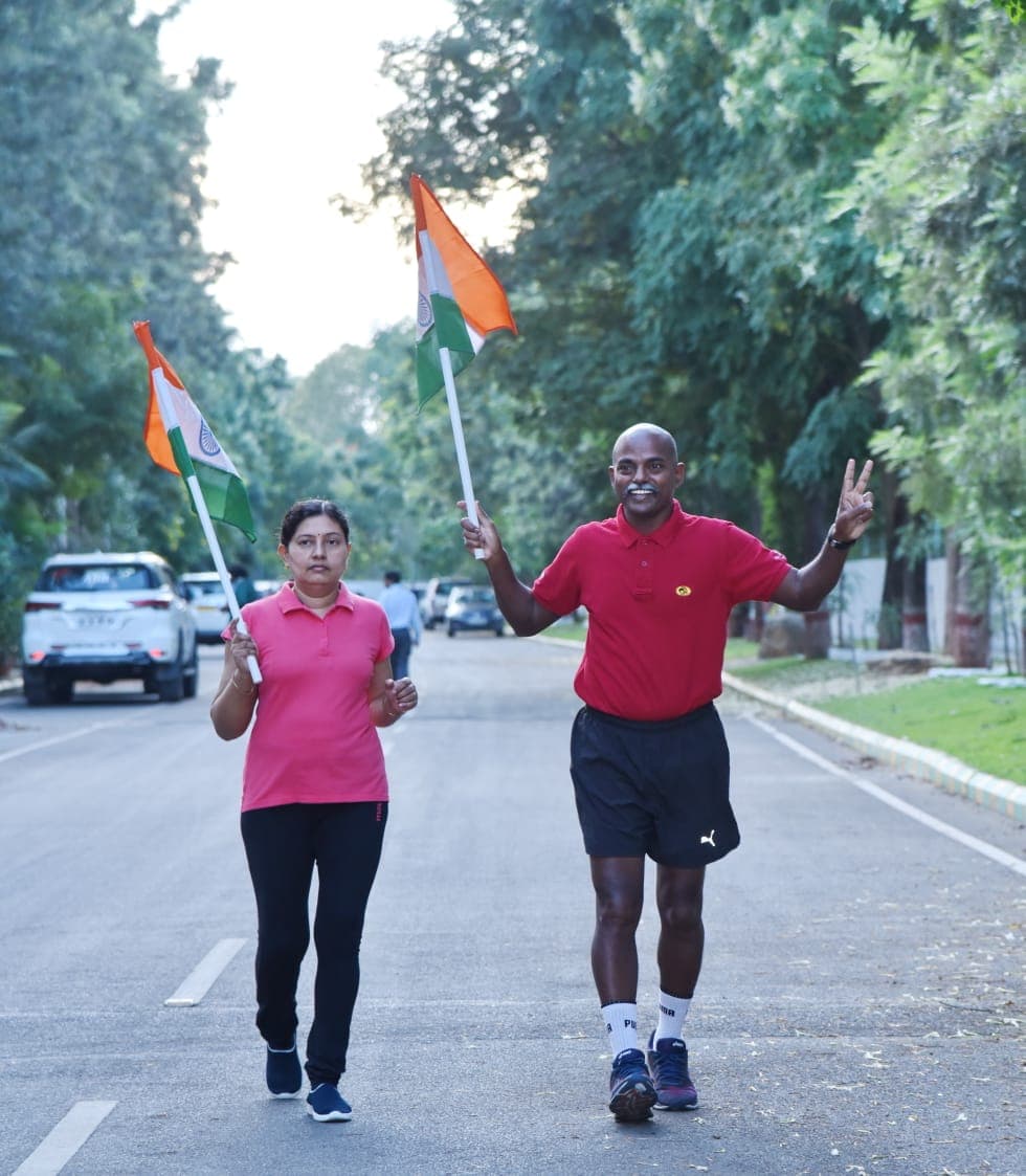 Bobba Ravinder Reddy and his wife walking with Indian flags on a tree-lined road